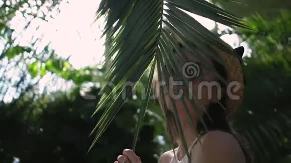 一个女孩用棕榈叶摆姿势的肖像视频的预览图