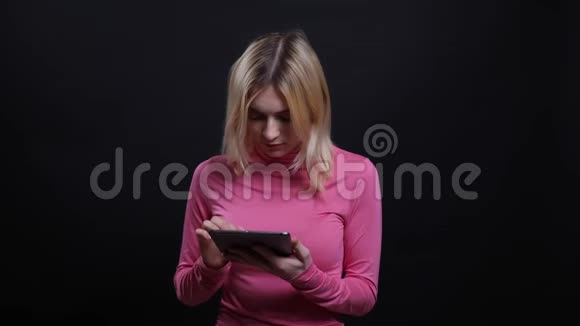 在镜头前的平板电脑上用社交媒体拍摄年轻漂亮金发女性的特写镜头视频的预览图