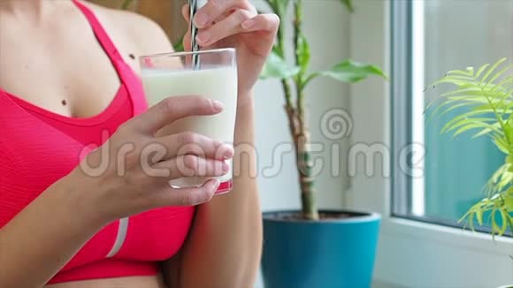 运动女孩喝着靠近窗户的奶昔慢悠悠地说视频的预览图
