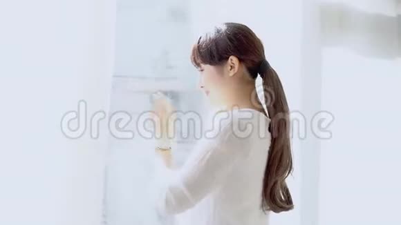 美丽的肖像年轻的亚洲女人打开窗户在卧室里看着并打招呼视频的预览图