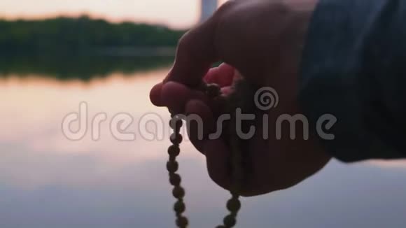 特写镜头男子手握小玫瑰花河畔晚祷视频的预览图