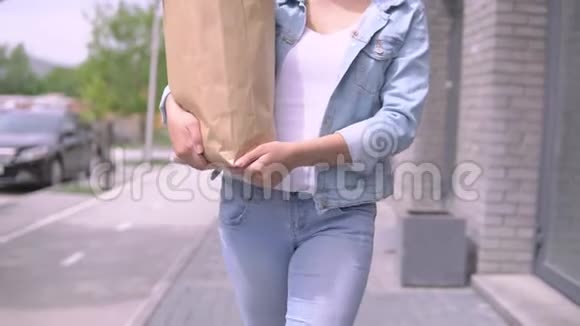 一个年轻漂亮的女人穿着牛仔夹克和帽子带着一个购物袋心情愉快微笑着4K视频的预览图