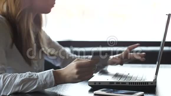 年轻女子在笔记本电脑上输入信用卡号码在网上支付公用事业账单视频的预览图