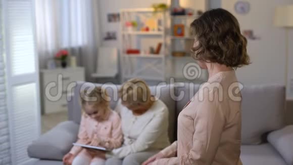 年轻的母亲欣赏女儿和祖母一起玩平板电脑视频的预览图