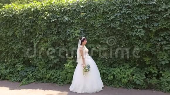 一位快乐的新娘带着一束鲜花在公园散步的肖像视频的预览图