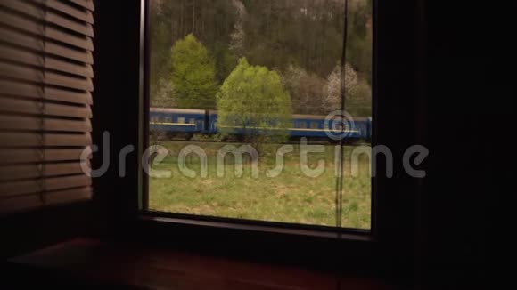 从私人住宅的窗户上可以看到欧洲火车沿着一条铁路在美丽的青山视频的预览图