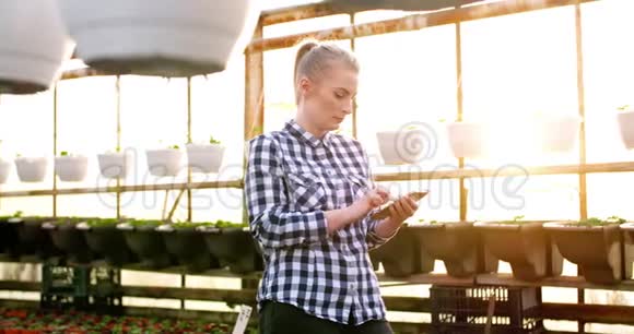 女植物学家在温室里用计算器视频的预览图