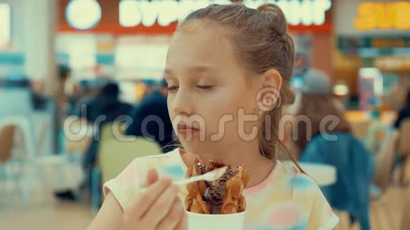 可爱的少年女孩在食物场吃冰淇淋年轻女孩在商场咖啡厅享用冰淇淋甜点视频的预览图