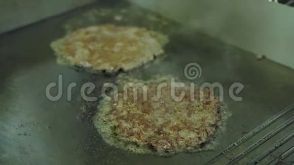 做汉堡在厨房里用专业的平底锅煎汁切菜视频的预览图