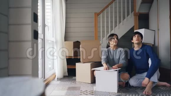 有魅力的年轻女人爱的女朋友正在和她的男朋友说话然后给他房子钥匙坐在新的地板上视频的预览图