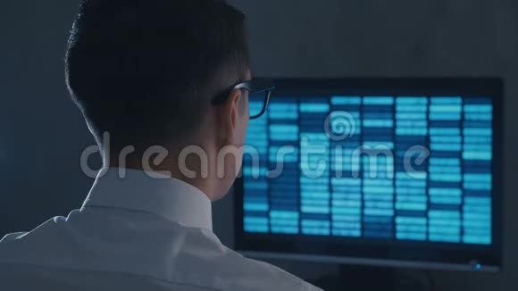 戴眼镜的专业IT极客程序员在夜间办公室用二进制代码工作视频的预览图