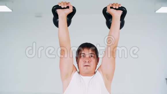人用水壶铃做蹲式动作工作室里的一个人举起重物做一个蹲视频的预览图