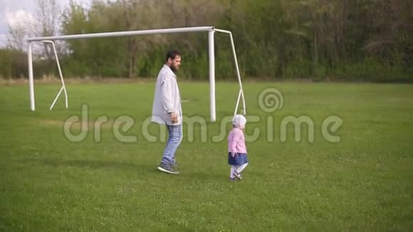 长胡子的父亲带着一个两岁的小女儿在绿草上视频的预览图