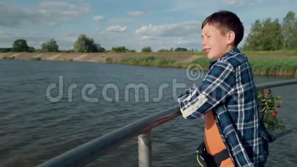 快乐的男孩站在河边的码头上视频的预览图