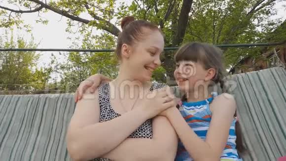生活方式的女人和女儿坐在花园秋千上父母和孩子之间的家庭关系视频的预览图