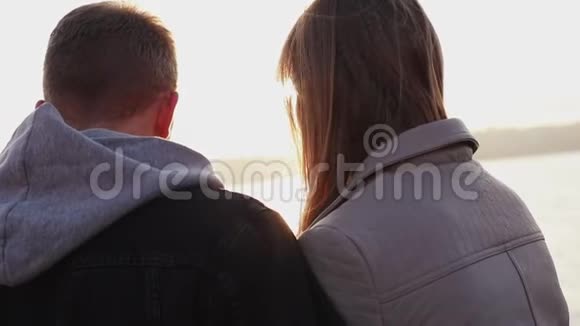 日落时分一对幸福的夫妇坐在湖边视频的预览图