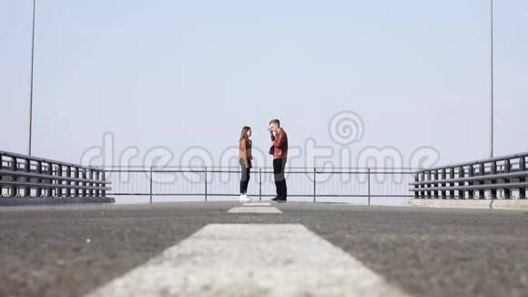 远处的大路上金发男站在可爱的女孩旁边打电话视频的预览图
