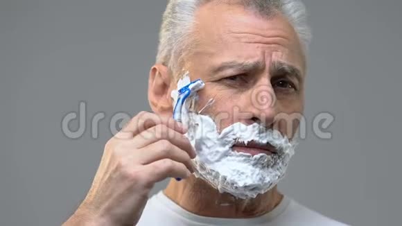 脸上有泡沫的老人刮胡子准备约会卫生视频的预览图