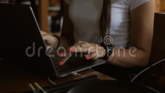 一个年轻女孩坐在咖啡馆里用笔记本电脑工作电脑键盘上的手指特写视频的预览图