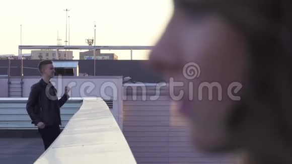 漂亮女人的脸远处穿夹克的金发帅哥在屋顶唱歌视频的预览图