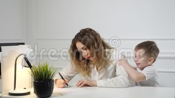 当小男孩在办公室工作时她正在打电话给他妈妈时她正在阻止他妈妈工作有工作的母亲视频的预览图