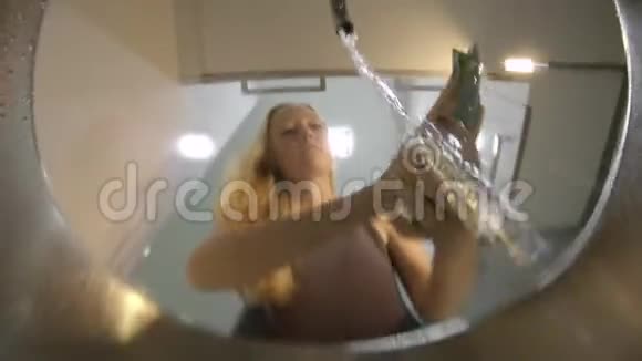当一个年轻的女人洗盘子时水槽里的景色视频的预览图