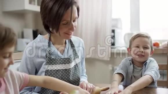 妈妈展示如何用正确的方法制作饼干帮助她的儿子他批准了它视频的预览图