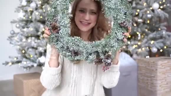 圣诞树背景下一位穿着白色毛衣微笑的女士的新年画像视频的预览图