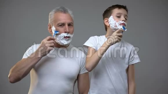 快乐的成年男人和青春期前的男孩刮胡子孩子教做人早上的仪式视频的预览图