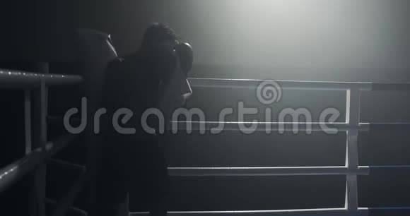 疲惫的男拳手拿着毛巾休息在拳场边缘拳击手经过艰苦训练后休息视频的预览图