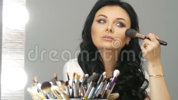 一幅美丽的蓝眼睛女模特的肖像长着黑色的头发坐在镜子前用一种视频的预览图