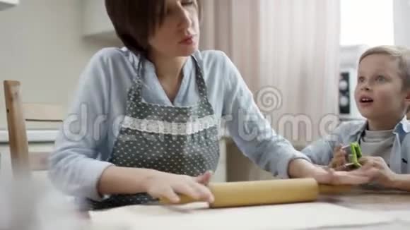 妈妈在厨房的桌子上用面团做饼干儿子把注意力放在妈妈身上视频的预览图