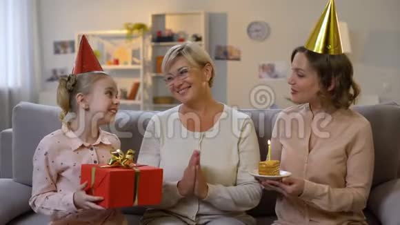 戴着派对帽的女孩子和妈妈送礼物庆祝奶奶的生日视频的预览图