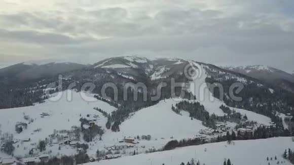 日出时一个山村的空中全景鸟瞰群山中白雪覆盖的房屋农村视频的预览图