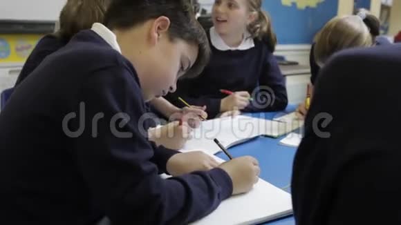 教师帮助学生在餐桌上工作视频的预览图