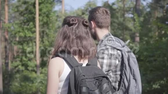 在森林里散步的男人和年轻女人的肖像一对旅行者带着背包在户外休闲夫妇视频的预览图