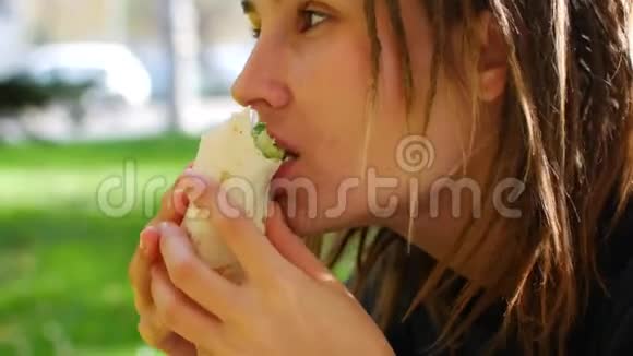 年轻的有着可怕的臀部的时髦女孩吃烤串女孩在公园里吃快餐晴天视频的预览图