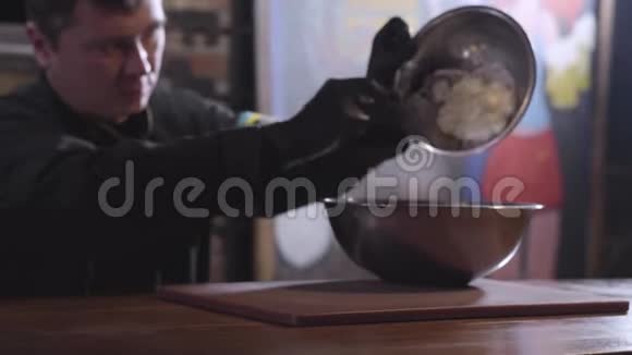 库克把面团从小碗到大碗使用勺子关闭厨师的身材模糊了准备现代食品视频的预览图