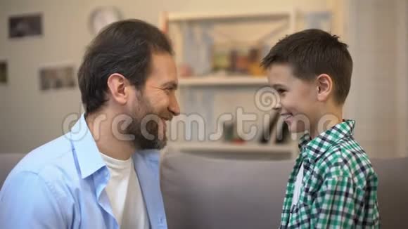 微笑的父亲和小儿子抚摸额头信任的关系朋友视频的预览图