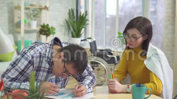 成年男性自闭症患者和医生在家学习画画视频的预览图