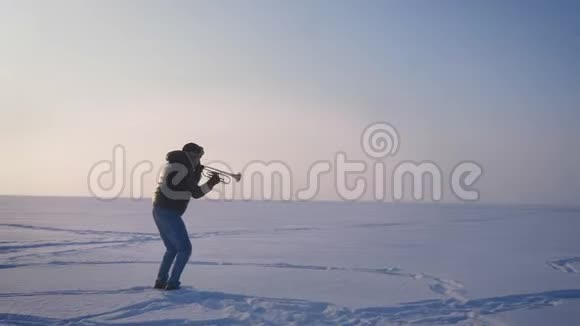 在吹喇叭和把它向上放在冰冻的自然背景上的个人资料中绕着乐手的镜头旋转视频的预览图