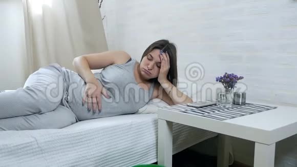 晨吐年轻的孕妇躺在沙发上吐在桶里妊娠中毒视频的预览图