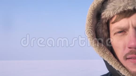 在雪漠背景下中年探险家戴着头巾微笑地看着太阳的特写半肖像视频的预览图