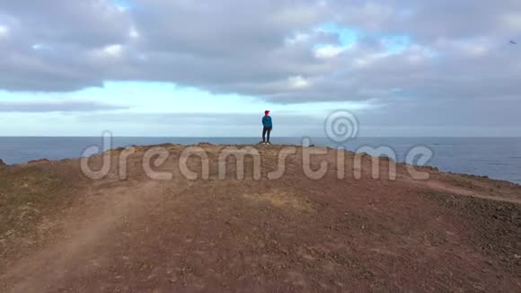 骑着运动服的女人坐在岩石上在海岸的一个保护区欣赏风景视频的预览图