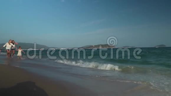 幸福的母亲带着两个女儿沿着南海海滩奔跑亚龙湾慢动作股票录像视频的预览图