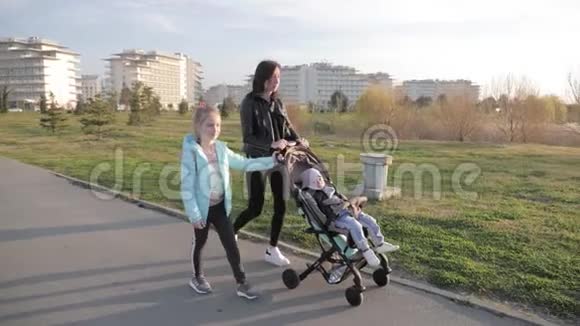 妈妈带着婴儿车和两个孩子在街上散步视频的预览图