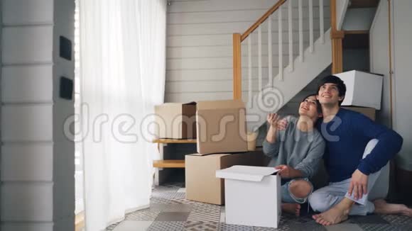 年轻人夫妻正坐在楼梯附近的新房子的地板上在做梦视频的预览图