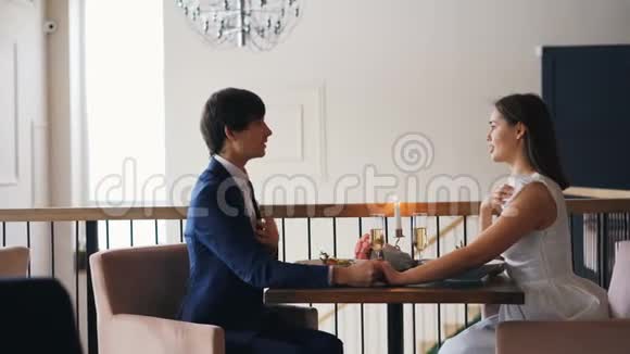 有爱心的年轻人正在餐厅里和一个快乐的女孩求婚她坐在桌旁给她戒指视频的预览图