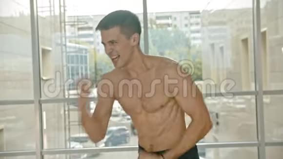 一个运动型的赤膊男拳击手站在窗边用影子耐力进行了一场比赛视频的预览图