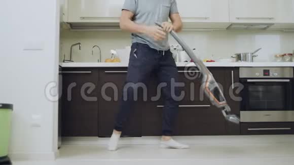 特写男人腿清洁地板与吸尘器在厨房视频的预览图